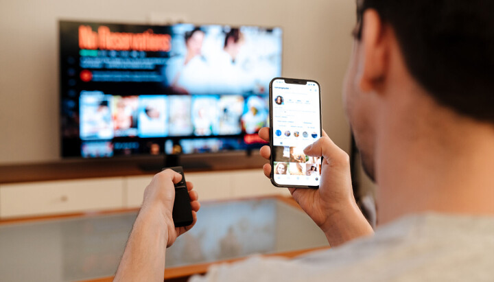 Nye kringkastingsreglar trer i kraft 1.mai. Mann som streamer, samtidig som han ser på mobilen. Medietilsynet