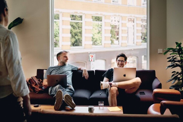 Netlife søker innholdsdesigner Too menn som sitter på sofaen med pc.