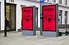 To røde Benjamin-plakater på digitale tavler langs et fortau i bygate