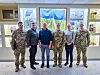 Sivile og militære representanter står foran ukrainsk flagg ved forsvarsuniversitet.