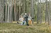 Filmcrew med kamera og boom-mikrofon står blant høye trær i skogen.