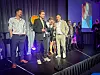 NettsiderCure-team på scenen mottar pris for arbeid med Lyngvær Lodges.