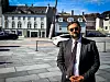 Andrew Bard Epstein står foran en steinlagt plass med klassiske bygninger og biler i bakgrunnen.