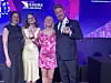 Tre personer står på en prisutdeling og holder glasspriser foran en Sabre Awards-bakgrunn.