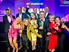 Gruppe av prisvinnere på scenen med pokaler foran en lilla Sabre Awards-bakgrunn.