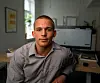 En mann sitter ved et skrivebord foran en dataskjerm i et kontor.