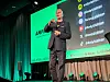 Andy Stalman står på en scene ved siden av en stor presentasjonsskjerm med branding- og sosiale medier-innhold.
