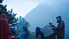 Turgåere står samlet med kart i et tåkelagt fjellandskap ved skogkanten.