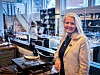 Lise-Karin Redfern står ved en Arven 1868-utstilling med historiske kjøkkenredskaper i et lyst lokale.