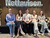 Fire personer sitter i en sofagruppe foran et Nettavisen-skilt i et moderne kontor.
