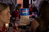 Opplyst høyttaler med «Streets of Light» på et bord i en mørk klubb med gjester rundt.