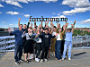 Gruppe av mennesker som står sammen på en brygge og feirer foran skiltet forskning.no.
