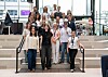 Stor gruppe mennesker poserer på en trapp i et lyst atrium med glassvegger.