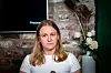 Hanna Oftedal Negård foran en murvegg, med skjerm og blomster i bakgrunnen.