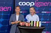To personer står foran en Coop-vegg med en rad drikkevarer på et svart bord.