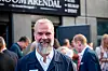 Paal Fure står foran en bygning med skilt, med flere personer og en åpen dør i bakgrunnen.