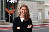 Smilende kvinne med korslagte armer foran en bygning med Vipps-logo.