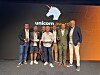 Gruppe personer poserer på en scene foran en skjerm med logoen «unicorn_awards».
