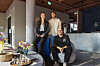 Fire personer poserer i en moderne restaurant med blomster og bardisk.