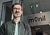 Mann med briller og skjegg foran et Monil-skilt i et kontorbygg.